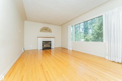 Hardwood flooring, fireplace with white mantel, and large picture window with extensive outdoor scenery - 