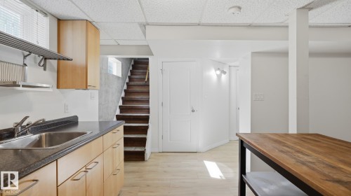 Light wood-finish flooring, recessed lighting, wood-finish cabinetry, stainless steel sink, and dark countertop - 11836 62 Street Nw, Edmonton, AB 