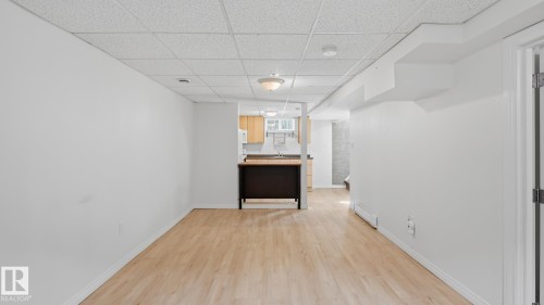 Open-concept living space featuring wood-finish flooring, white walls, and a drop ceiling - 11836 62 Street Nw, Edmonton, AB 