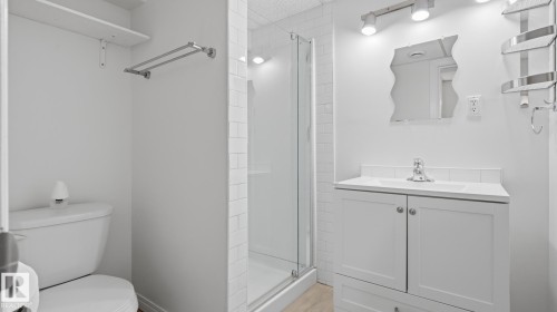 White vanity with a single basin sink, wall-mounted mirror, and overhead track lighting - 11836 62 Street Nw, Edmonton, AB 