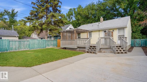 Rear exterior featuring yellow siding, a multi-level wood deck, an attached wood pergola, a concrete patio, and a grass lawn - 11836 62 Street Nw, Edmonton, AB 