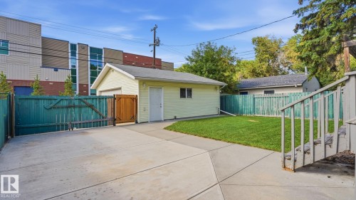 Detached garage with siding exterior, concrete driveway, and a wooden fence enclosing a grass lawn - 11836 62 Street Nw, Edmonton, AB 