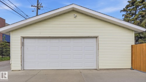Detached garage featuring panel siding, an overhead door, and a concrete driveway - 11836 62 Street Nw, Edmonton, AB 