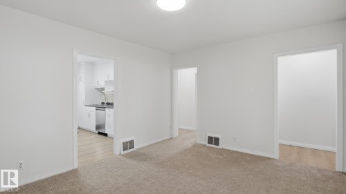 Recessed ceiling lighting, light-colored carpeting, white wall finishes, and a kitchen with stainless steel appliances - 11836 62 Street Nw, Edmonton, AB 