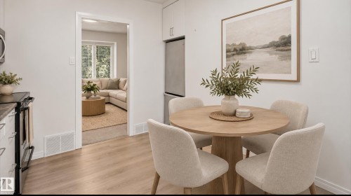 Kitchen area with wood-finish flooring, white cabinetry, a built-in microwave, and a stainless steel refrigerator - 11836 62 Street Nw, Edmonton, AB 
