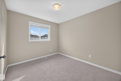 Neutral wall paint, ceiling-mounted light fixture, white trim, grey carpeting, and a window with a white frame - 483 Watt Boulevard Sw, Edmonton, AB 