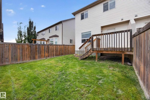 Private fenced yard featuring a wooden deck with railing and stairs to the lawn - 483 Watt Boulevard Sw, Edmonton, AB 