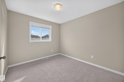 Neutral wall paint, ceiling-mounted light fixture, white trim, grey carpeting, and a window with a white frame - 