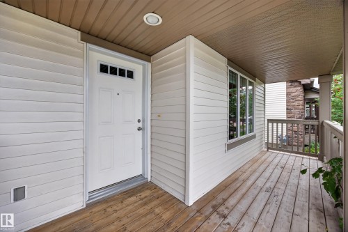 Inviting covered porch with wood-finish decking, white siding, and multi-pane window - 483 Watt Boulevard Sw, Edmonton, AB 