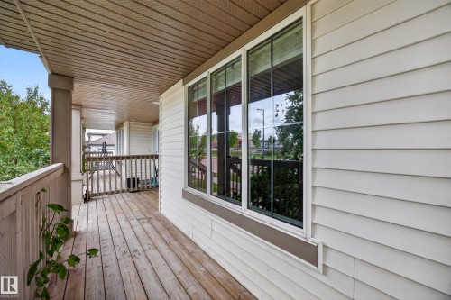 Covered outdoor porch featuring wood flooring, wood railings, and a horizontal siding exterior - 483 Watt Boulevard Sw, Edmonton, AB 