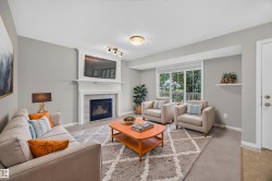 Living space featuring a built-in fireplace with a white mantel, track lighting, and a large window - 