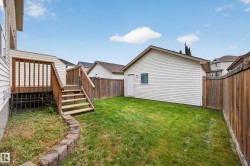 Expansive grassy yard area with a detached structure, wood privacy fencing, and an elevated wood deck with stairs - 