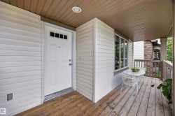 Inviting covered porch with wood-finish decking, white horizontal siding, and multiple windows - 