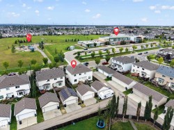 Aerial perspective of a residential neighborhood with detached homes, green spaces, and community buildings - 