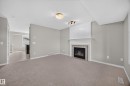 Neutral wall paint, fireplace with a decorative mantel, tiled hearth, recessed lighting, and carpeted flooring - 483 Watt Boulevard Sw, Edmonton, AB 