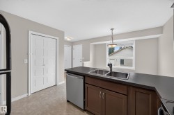 Kitchen featuring dark wood-finish cabinetry, a dual basin stainless steel sink, and a stainless steel dishwasher - 