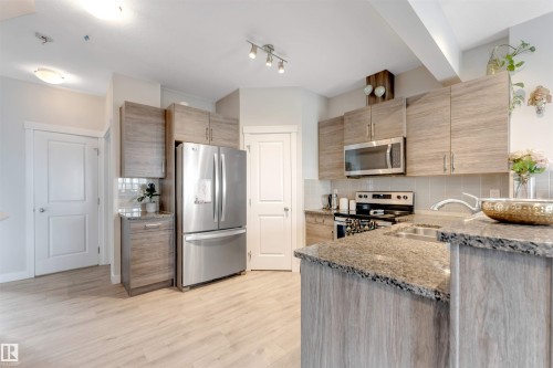 Kitchen featuring wood-finish cabinetry, stainless steel appliances, granite countertops, and wood-finish flooring - 2004 15 Avenue Nw, Edmonton, AB 