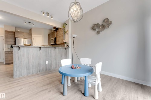 Open concept kitchen area with wood-finish flooring, stainless steel appliances, and a breakfast bar with a light wood-look finish - 2004 15 Avenue Nw, Edmonton, AB 
