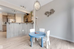 Open concept kitchen area with wood-finish flooring, stainless steel appliances, and a breakfast bar with a light wood-look finish - 