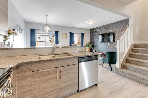 Kitchen with granite countertops, wood-finish cabinetry, and a stainless steel dishwasher - 2004 15 Avenue Nw, Edmonton, AB 