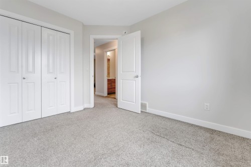 Neutral-toned carpeting, white bi-fold closet doors, and white interior doors - 2004 15 Avenue Nw, Edmonton, AB 