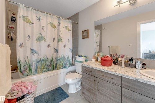 Bathtub with subway tile surround, wood-finish vanity with a light-toned countertop, and an integrated sink - 2004 15 Avenue Nw, Edmonton, AB 