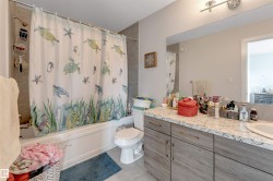 Bathtub with subway tile surround, wood-finish vanity with a light-toned countertop, and an integrated sink - 