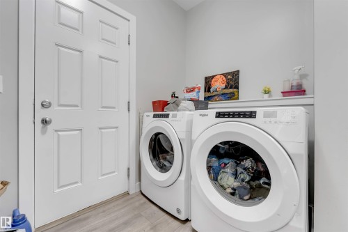 Dedicated laundry space featuring a built-in shelf, light-toned walls, and wood-finish flooring - 2004 15 Avenue Nw, Edmonton, AB 