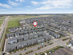 Expansive residential community featuring a variety of detached homes and townhomes, surrounded by open green spaces and a multi-lane roadway - 