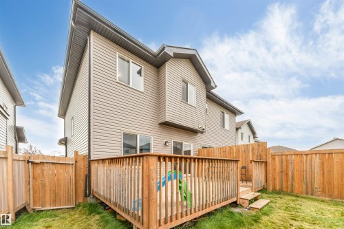 Two-story exterior with siding, featuring a wooden deck with railing, a wooden privacy fence, and a grassy lawn - 2004 15 Avenue Nw, Edmonton, AB 