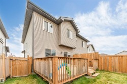 Two-story exterior with siding, featuring a wooden deck with railing, a wooden privacy fence, and a grassy lawn - 
