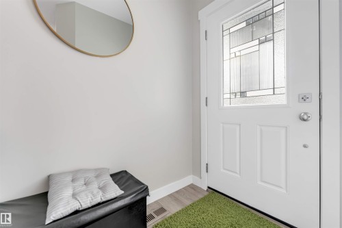 Entryway featuring a white door with decorative glass paneling, light wood-finish flooring, and white wall trim - 2004 15 Avenue Nw, Edmonton, AB 