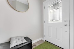 Entryway featuring a white door with decorative glass paneling, light wood-finish flooring, and white wall trim - 