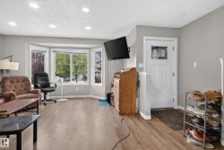 Recessed lighting, wood-finish flooring, bay window, white paneled door, and neutral wall paint - 