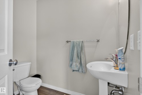 Pedestal sink with chrome faucet, toilet, and wood-finish flooring - 7817 Schmid Place Nw, Edmonton, AB 