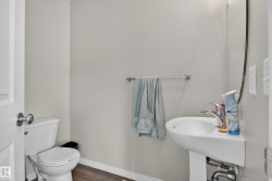 Pedestal sink with chrome faucet, toilet, and wood-finish flooring - 