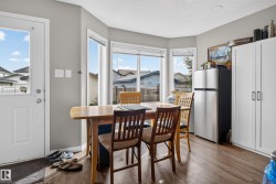 Wood-finish flooring, bay window, white paneled door, stainless steel refrigerator, and built-in white cabinetry - 