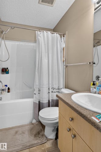 Bathtub with shower, toilet, and vanity with an integrated sink - 7817 Schmid Place Nw, Edmonton, AB 
