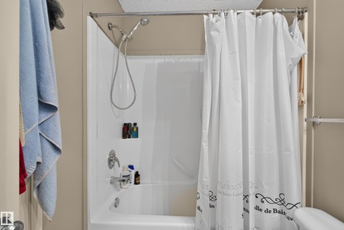 Bathtub and shower combination with a bright white finish, featuring a chrome showerhead and faucet - 7817 Schmid Place Nw, Edmonton, AB 