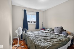 Wood-finish flooring with a window featuring blue curtains, light-colored walls, and a textured white ceiling - 