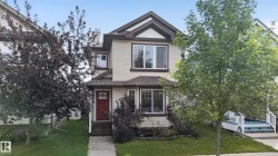 Two-story exterior with light-colored siding, dark trim accents, and a contrasting red front door - 