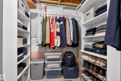 Built-in closet organization system featuring white shelving units, hanging clothes rods, and a multi-level shoe rack - 