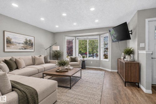 Recessed lighting, bay windows with white trim, wood-finish flooring, and a built-in media console - 7817 Schmid Place Nw, Edmonton, AB 
