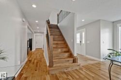 Hardwood flooring, recessed ceiling lighting, a wood staircase with black iron balusters, and a double-door entry with decorative glass inserts - 
