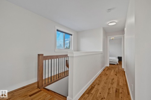Hardwood flooring throughout, contemporary wood and wrought iron staircase railing, white trim details, and a recessed ceiling light fixture - 12403 29A Avenue Nw, Edmonton, AB 