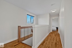 Hardwood flooring throughout, contemporary wood and wrought iron staircase railing, white trim details, and a recessed ceiling light fixture - 