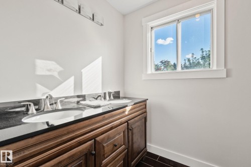 Dual vanity with inset wood-finish cabinetry, undermount sinks, and a dark countertop - 12403 29A Avenue Nw, Edmonton, AB 