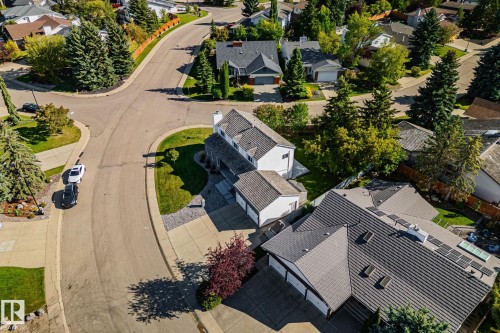 Paved roads winding through a residential area with mature landscaping, featuring a property with a multi-car garage, tiled roof, and integrated solar panels - 12403 29A Avenue Nw, Edmonton, AB 