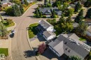 Paved roads winding through a residential area with mature landscaping, featuring a property with a multi-car garage, tiled roof, and integrated solar panels - 12403 29A Avenue Nw, Edmonton, AB 