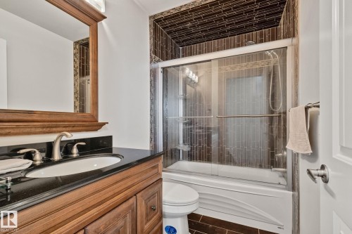 Wood-finish vanity with an undermount sink, black countertop, and brushed nickel faucet - 12403 29A Avenue Nw, Edmonton, AB 